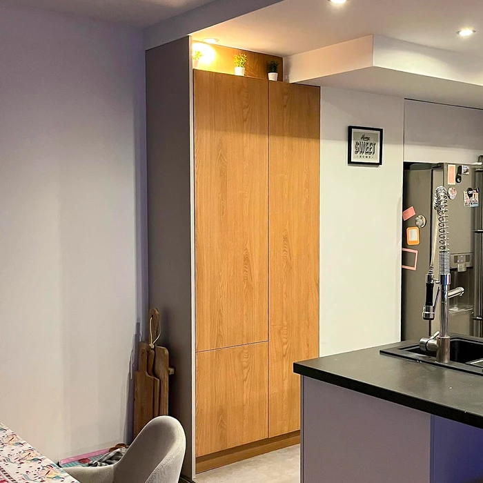 Cuisine moderne avec meuble colonne en chêne naturel à portes affleurantes, intégrant réfrigérateur