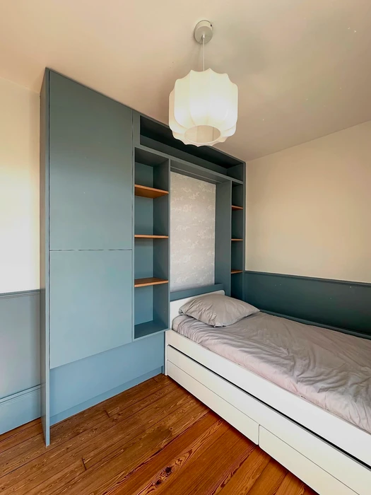 Chambre enfant compacte avec lit plateforme blanc à tiroirs gigognes, intégré dans un meuble sur mesure bleu-gris ardoise