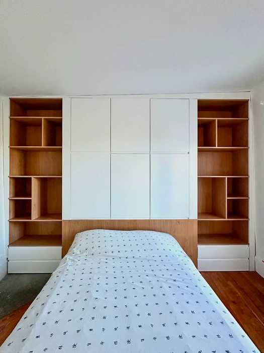 Chambre avec lit simple intégré dans un meuble sur mesure couvrant tout le mur