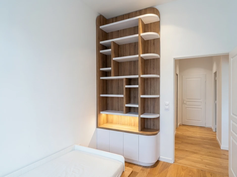 Salon minimaliste avec meuble mural sur mesure blanc mat, comprenant placards supérieurs à portes affleurantes, niches ouvertes, étagères en verre trempé avec supports dorés