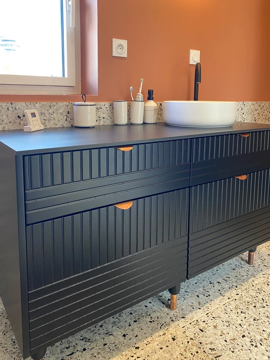 Salon moderne avec banquette d'angle sur mesure, assise en tissu gris clair, caissons de rangement blancs intégrés